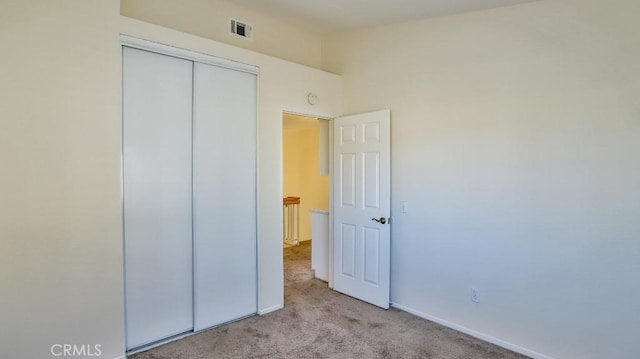 unfurnished bedroom featuring light carpet and a closet