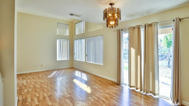 empty room featuring light wood-type flooring and an inviting chandelier