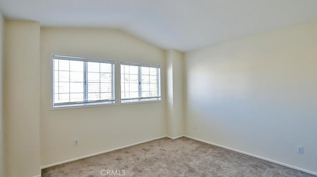 unfurnished room featuring light carpet and vaulted ceiling