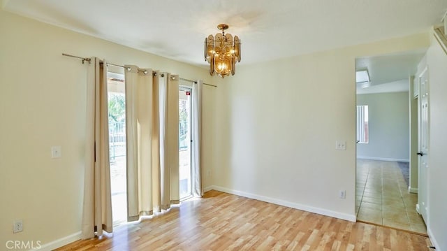 unfurnished room with light wood-type flooring and a chandelier