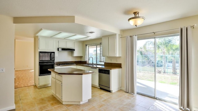 kitchen featuring appliances with stainless steel finishes, sink, white cabinetry, a kitchen island, and ventilation hood