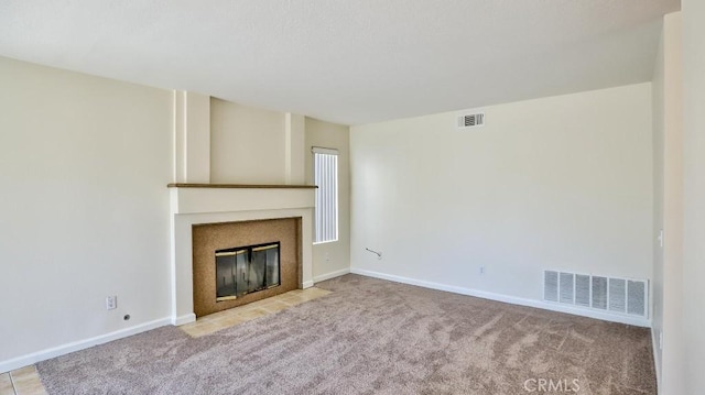 unfurnished living room with a tiled fireplace and light colored carpet