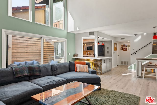 living room featuring light hardwood / wood-style floors and a towering ceiling