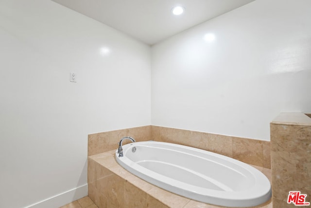 bathroom with a relaxing tiled tub and tile patterned floors