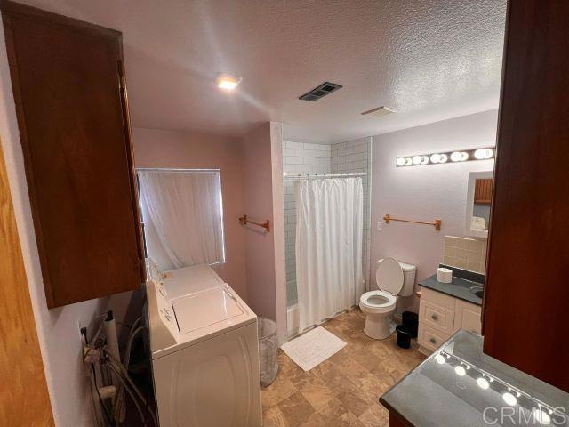 full bathroom featuring toilet, vanity, independent washer and dryer, shower / tub combo, and a textured ceiling