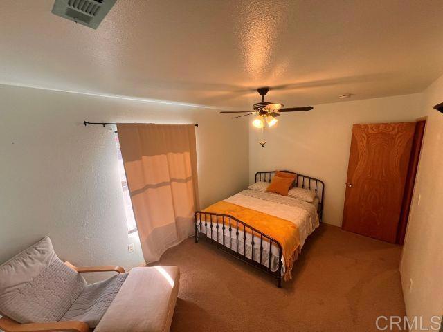 bedroom featuring ceiling fan, carpet, and a textured ceiling