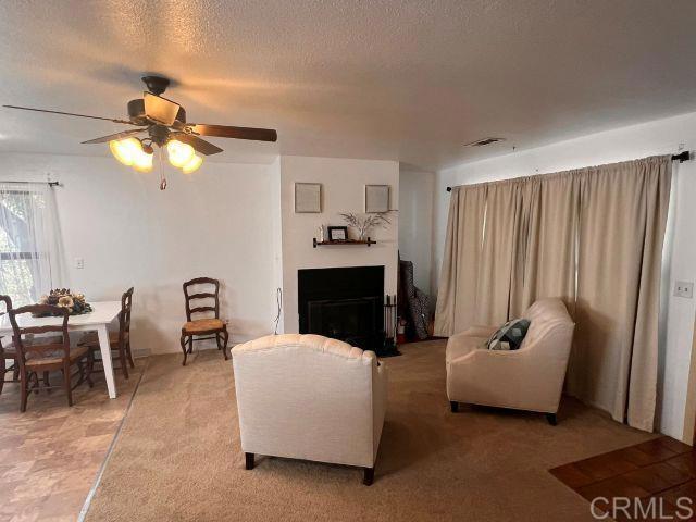 living room featuring ceiling fan and a textured ceiling