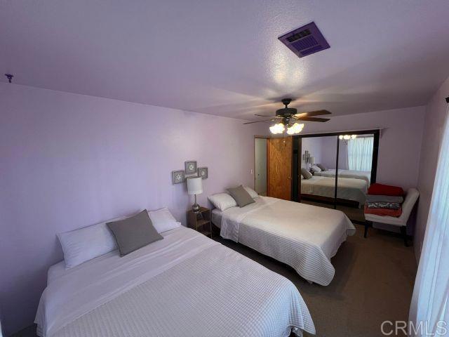 bedroom featuring ceiling fan, a textured ceiling, and dark colored carpet