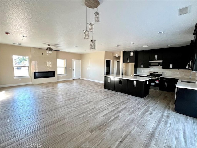 kitchen with stainless steel appliances, tasteful backsplash, a center island, pendant lighting, and sink