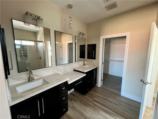 bathroom with wood-type flooring, walk in shower, and vanity