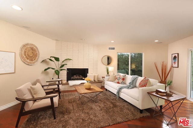 living room featuring dark hardwood / wood-style flooring and a brick fireplace