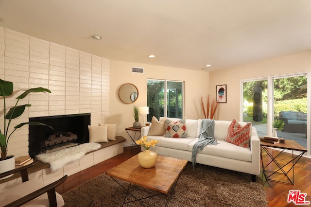 living room with a brick fireplace and dark hardwood / wood-style floors