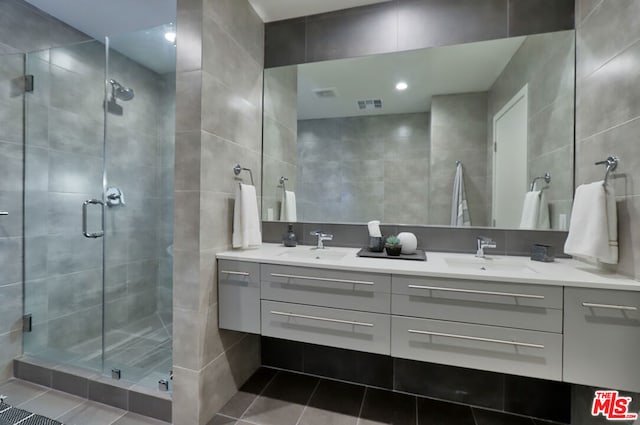 bathroom with an enclosed shower, vanity, tile walls, and tile patterned floors