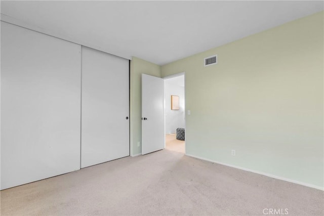 unfurnished bedroom with light colored carpet and a closet