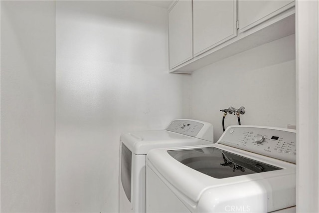 washroom with washing machine and clothes dryer and cabinets