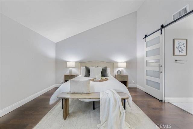 bedroom featuring dark hardwood / wood-style flooring, lofted ceiling, and a barn door