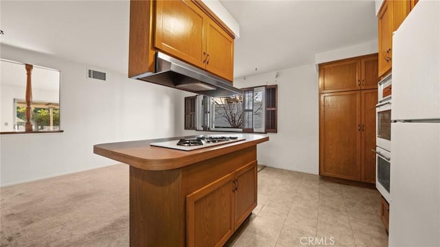 kitchen with light carpet, a breakfast bar, kitchen peninsula, and white appliances