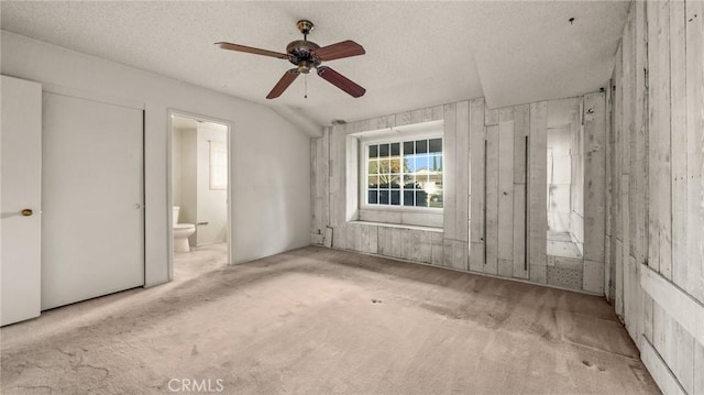 interior space featuring ceiling fan, light colored carpet, a textured ceiling, and ensuite bathroom