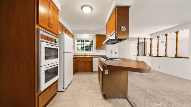 kitchen with a kitchen island, sink, white appliances, a kitchen breakfast bar, and wall chimney exhaust hood