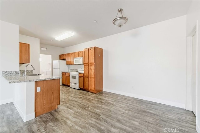 kitchen with kitchen peninsula, wood-type flooring, sink, white appliances, and light stone countertops