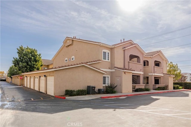 view of property featuring community garages and central AC unit