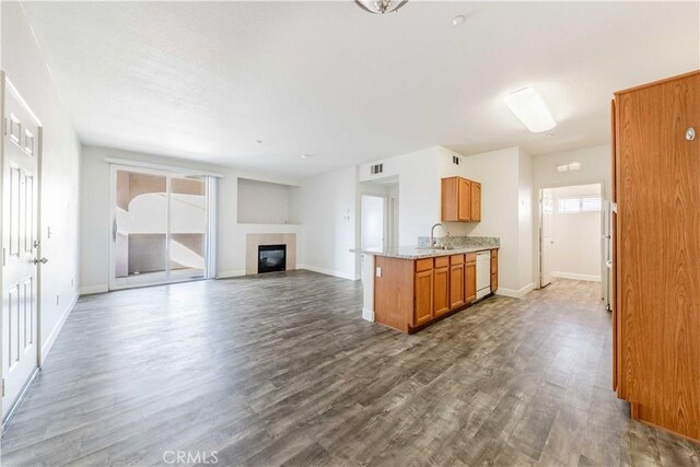 kitchen featuring white dishwasher, dark hardwood / wood-style floors, light stone counters, and sink