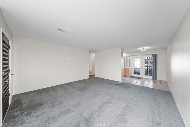 unfurnished room with light carpet and french doors