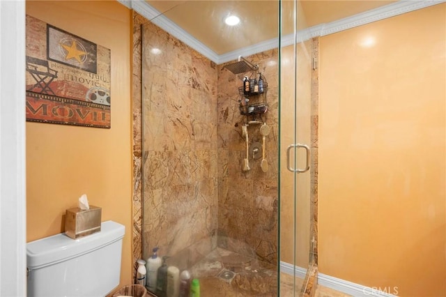 bathroom featuring toilet, crown molding, and a shower with shower door