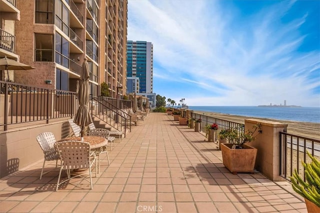 view of patio / terrace featuring a water view and a beach view