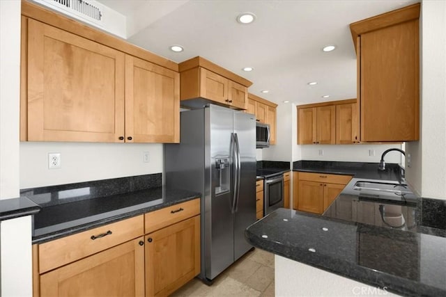 kitchen featuring dark stone countertops, sink, and appliances with stainless steel finishes