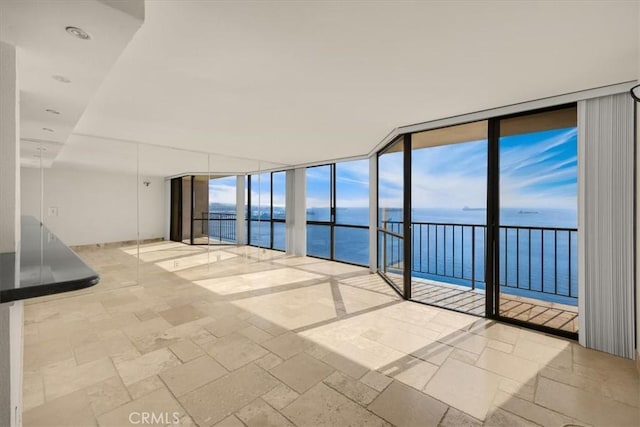 spare room featuring a water view and a wall of windows