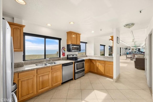 kitchen featuring a water view, stainless steel appliances, sink, and light tile patterned floors