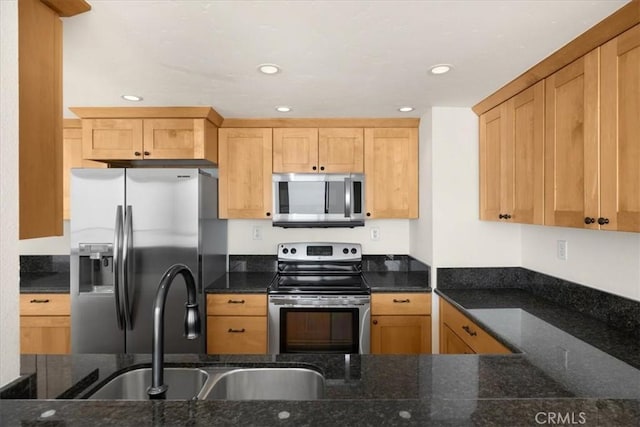 kitchen featuring appliances with stainless steel finishes, sink, light brown cabinets, and dark stone countertops