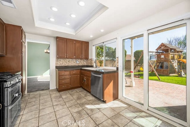 kitchen with tasteful backsplash, a raised ceiling, sink, appliances with stainless steel finishes, and light tile patterned floors