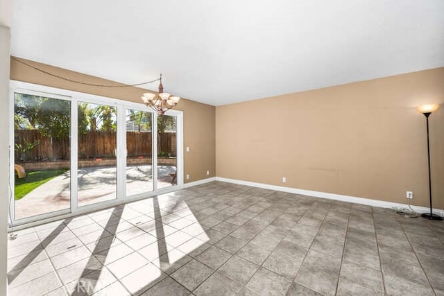 tiled spare room with a chandelier