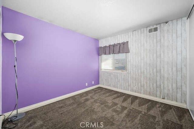 carpeted spare room with wooden walls