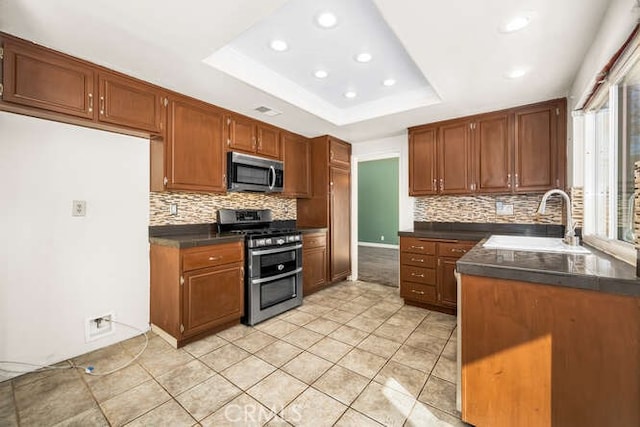 kitchen featuring light tile patterned floors, appliances with stainless steel finishes, a raised ceiling, and sink