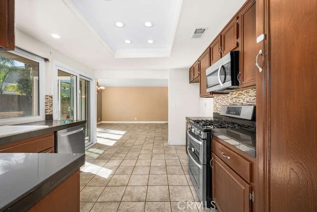 kitchen featuring light tile patterned floors, decorative backsplash, a tray ceiling, and stainless steel appliances