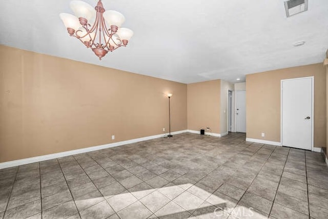 tiled spare room with a chandelier