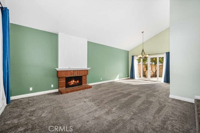 unfurnished living room with vaulted ceiling, a brick fireplace, a chandelier, and dark colored carpet