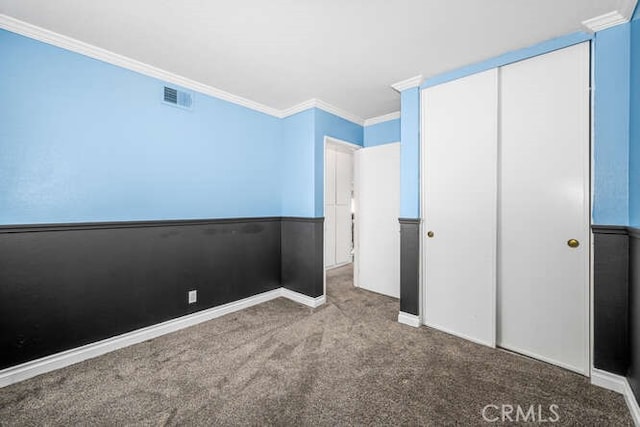 unfurnished bedroom featuring light colored carpet, a closet, and ornamental molding