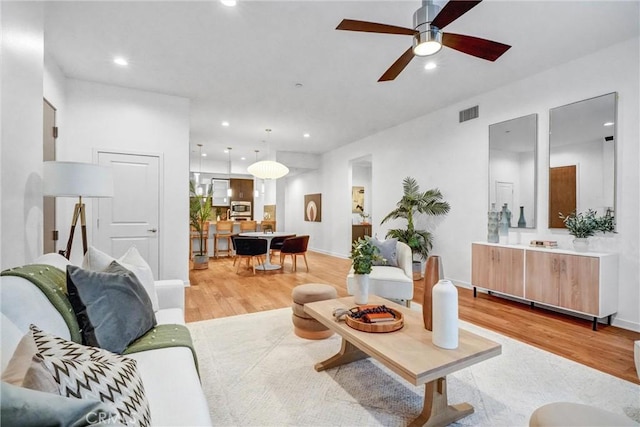 living room with ceiling fan and light hardwood / wood-style flooring