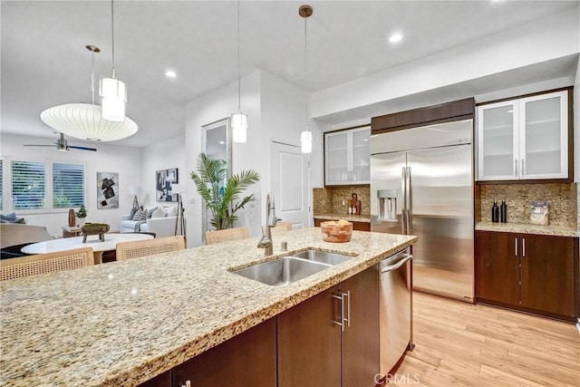 kitchen with pendant lighting, stainless steel appliances, decorative backsplash, sink, and ceiling fan