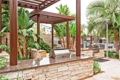 view of patio with an outdoor kitchen, a pergola, and area for grilling