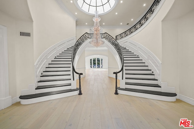 stairway with a high ceiling, wood-type flooring, and ornamental molding