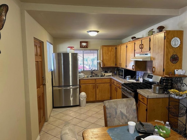 kitchen with tile counters, stainless steel appliances, decorative backsplash, sink, and light tile patterned floors