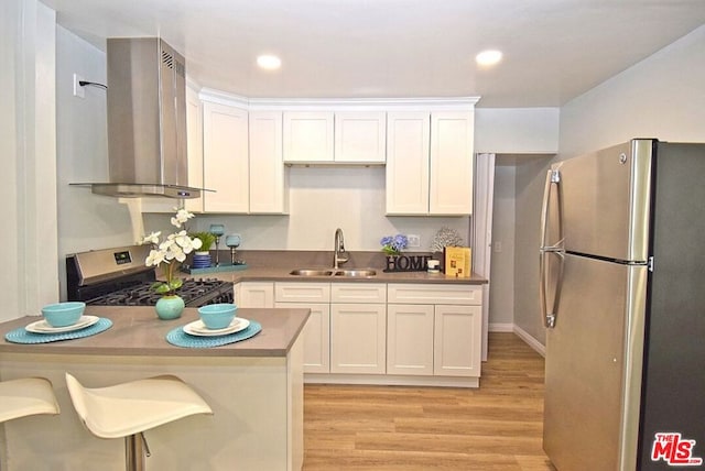 kitchen featuring light hardwood / wood-style floors, sink, white cabinetry, appliances with stainless steel finishes, and wall chimney exhaust hood