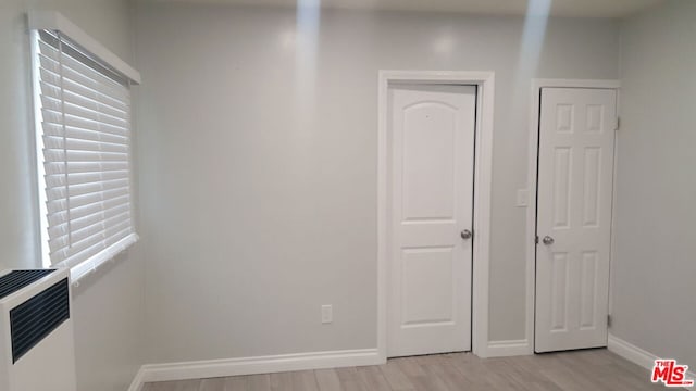 unfurnished bedroom with light wood-type flooring and heating unit