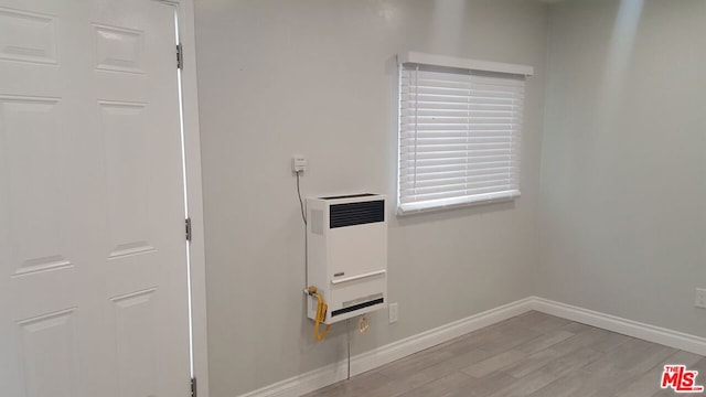 clothes washing area featuring heating unit and light hardwood / wood-style flooring