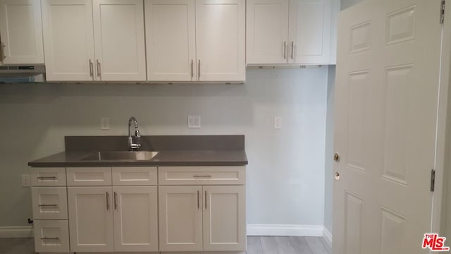 kitchen featuring white cabinets, sink, and light hardwood / wood-style floors